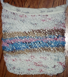 white tote bag with tan, pink, and blue stripes, knit out of recycled plastic bags and lined with white fabric